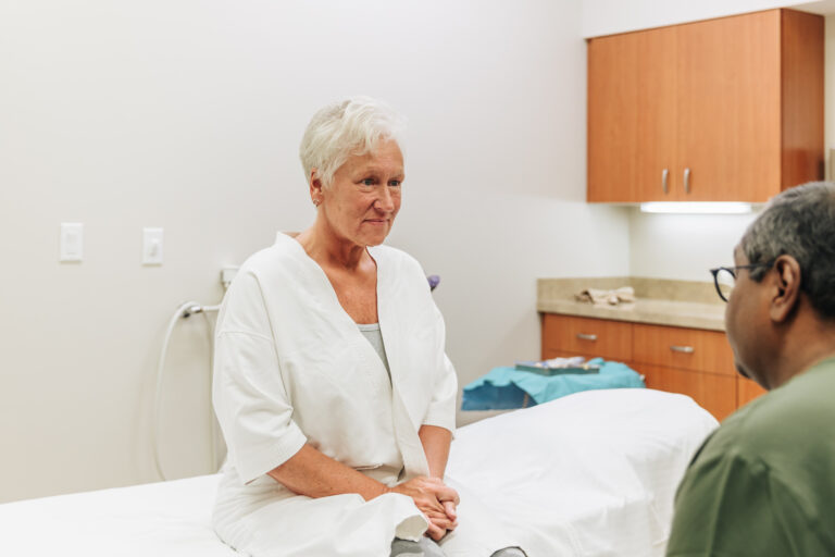 An elderly patient smiles as one of our providers explains the benefits of abdominoplasty in Kalamazoo