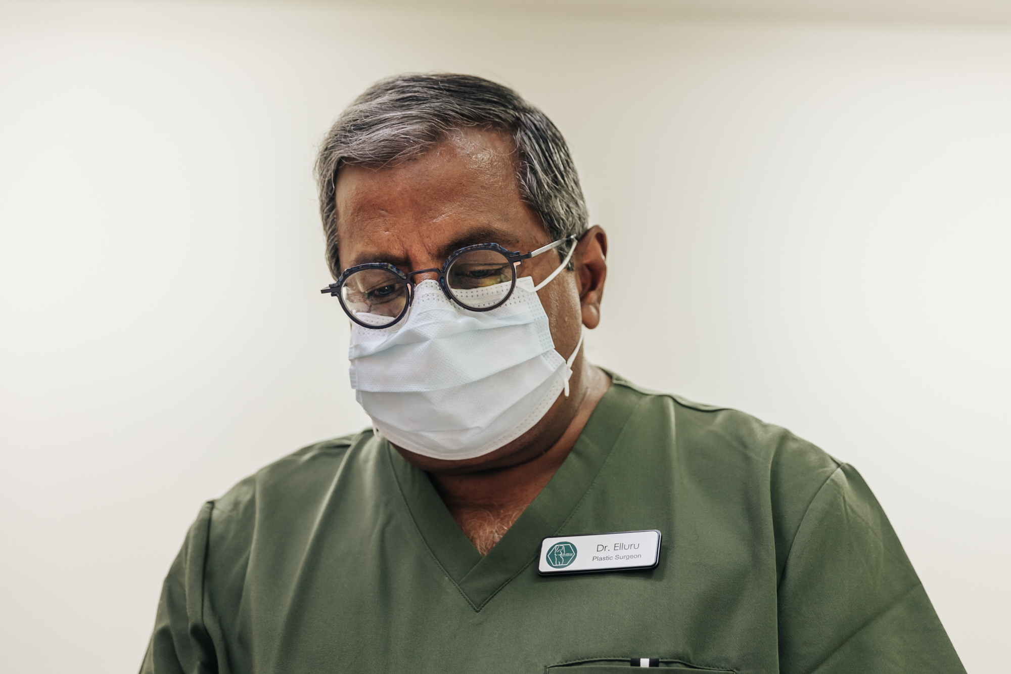Dr. Elluru, the best plastic surgeon in Kalamazoo, wears a face mask as he performs an exam.