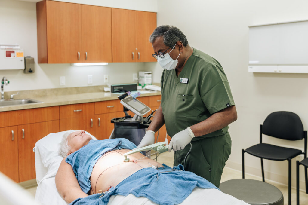 A provider in green scrubs performs the BodyTite procedure on a patient laying on his back as a part of our process for body sculpting near Battle Creek, MI.